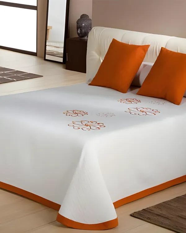 Cubrecama blanco con flores bordadas en naranja y dos cojines naranja