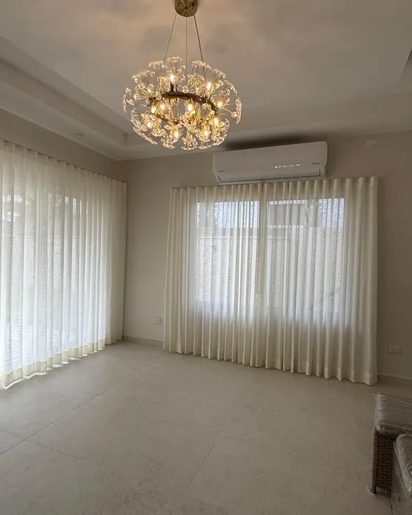 Cortinas Ripple Fold de velo de lino blanco, de suelo a techo, en las ventanas de una sala con lámpara de cristal