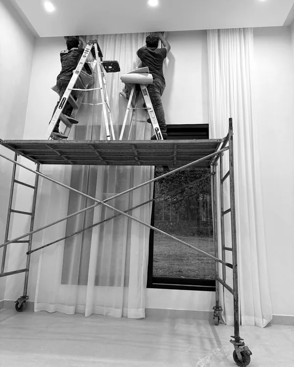 Instalación de cortinas de suelo a techo con andamio en un ventanal de doble altura